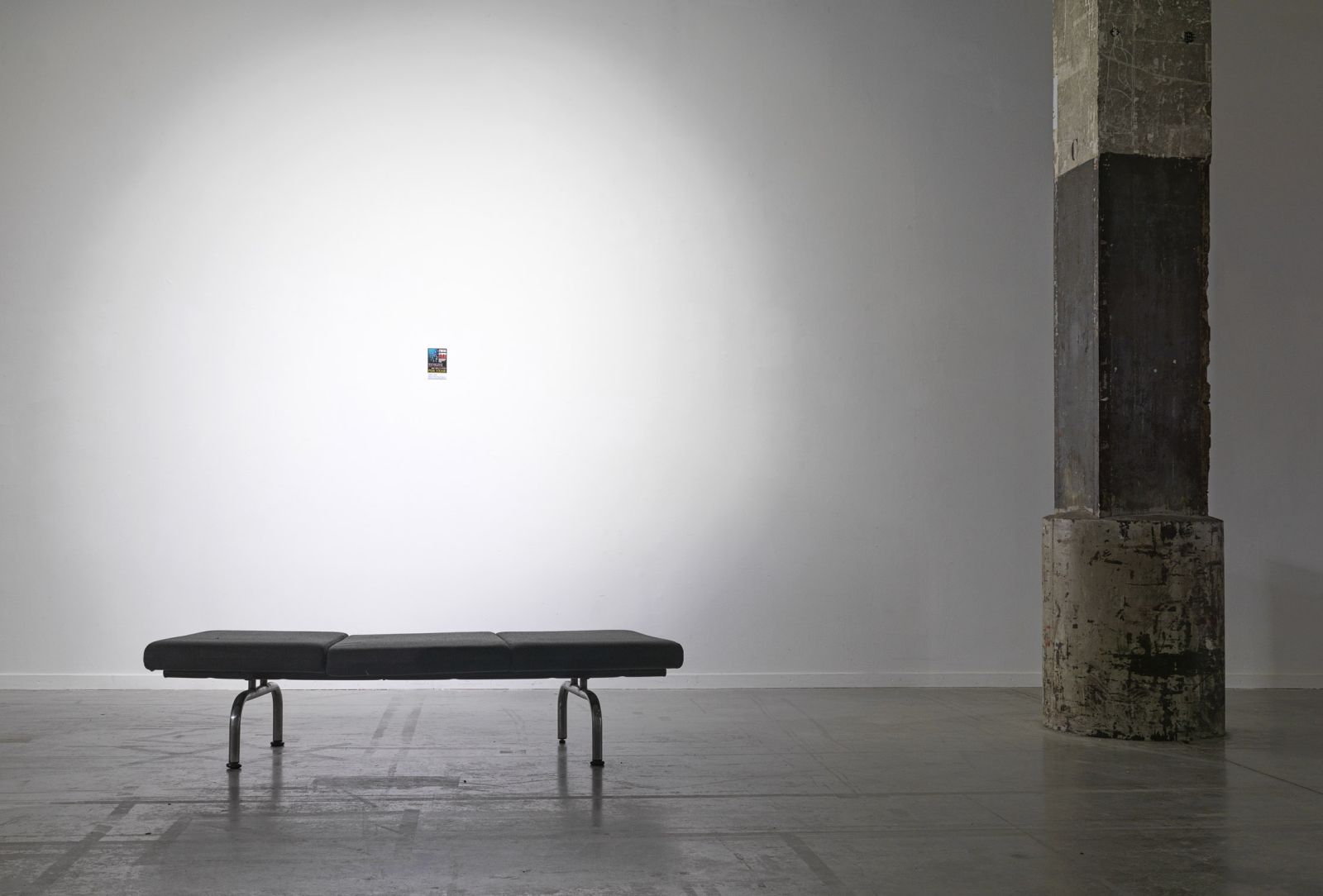 the stupid fish print hangs on a white wall by a bench and a pillar to the right of it, in the scene the print is so small it conveys significance