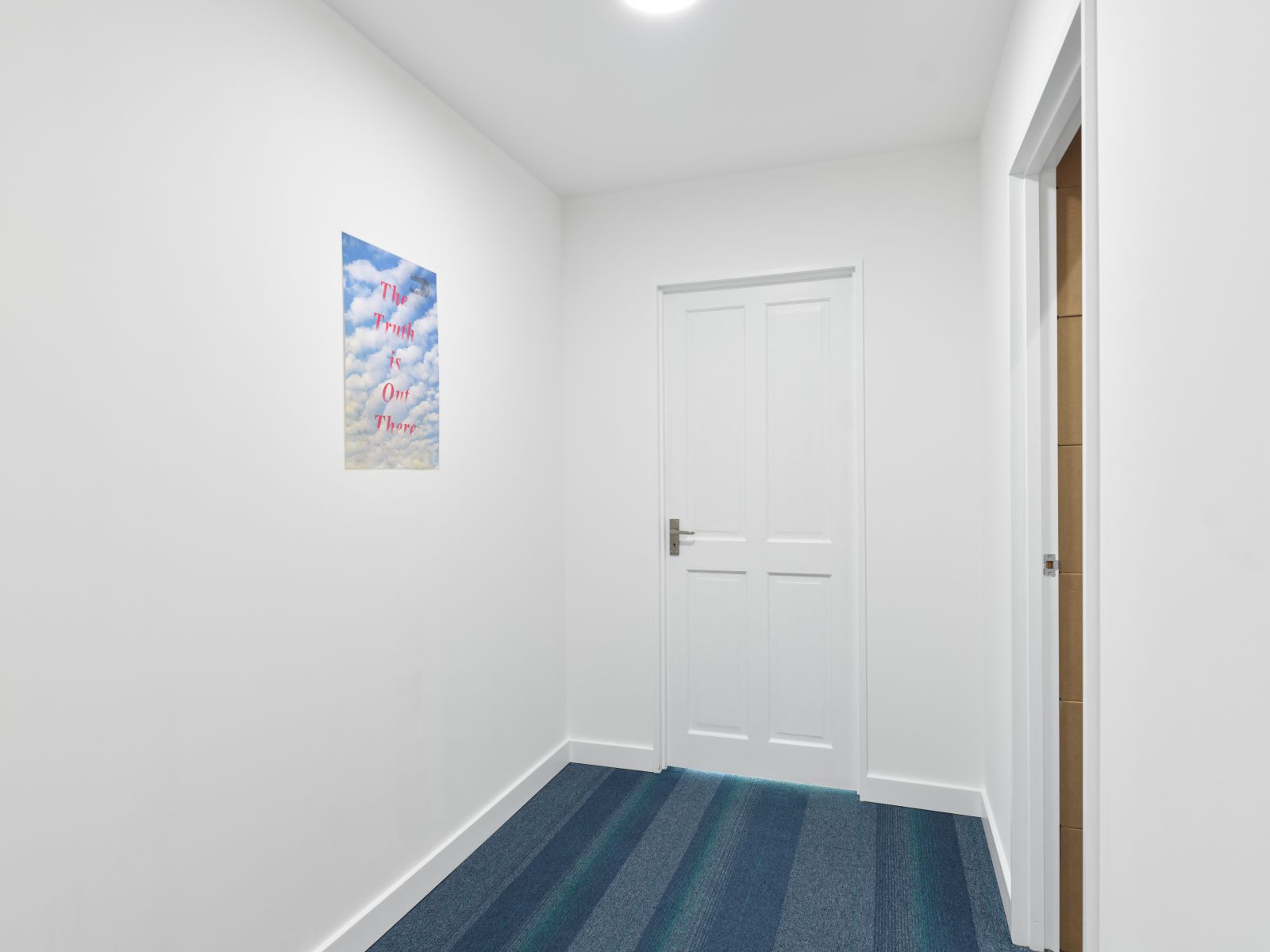 A bright hallway with blue striped carpet, showing a poster with the text 