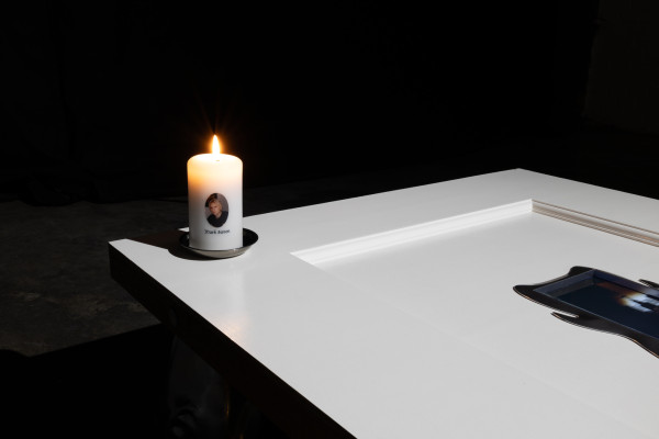 A close up of the scene with a candle that has Mark Savon's photograph on it and his name underneath